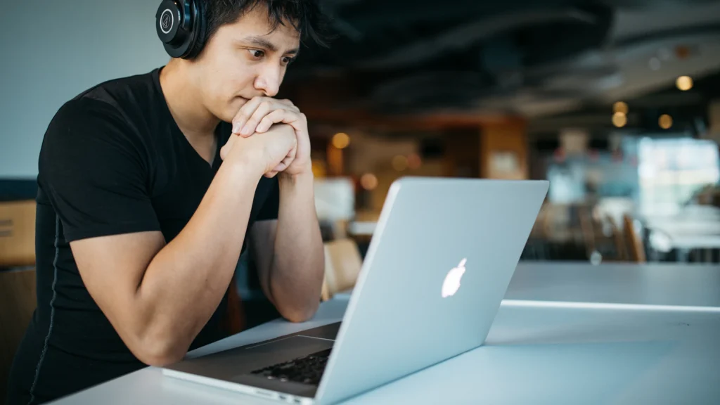 A young student with headphones studying on a laptop
