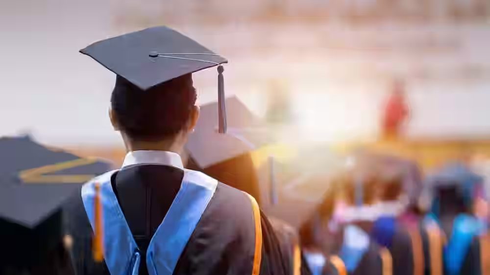 Graduate in cap and gown facing the ceremony