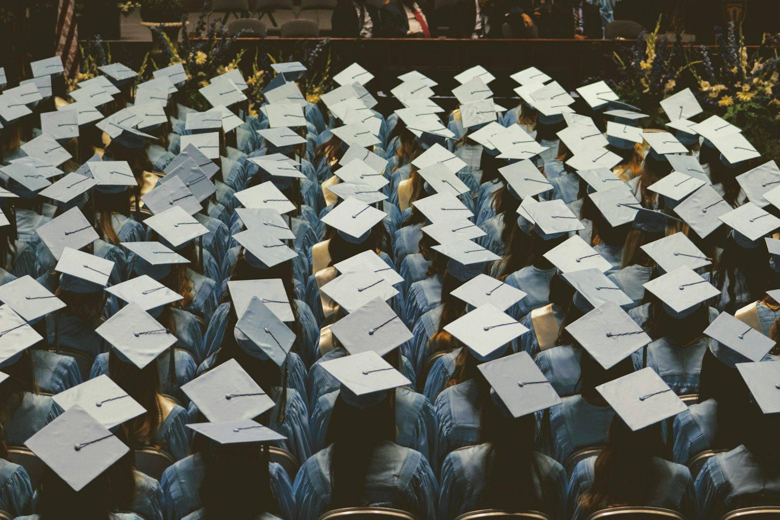 Graduates in light blue gowns and caps at a university ceremony